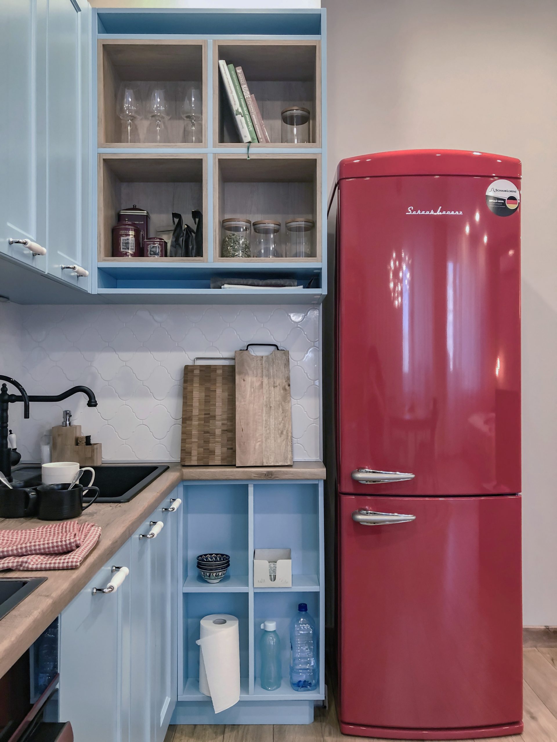 Отдельностоящий красный холодильник на кухне